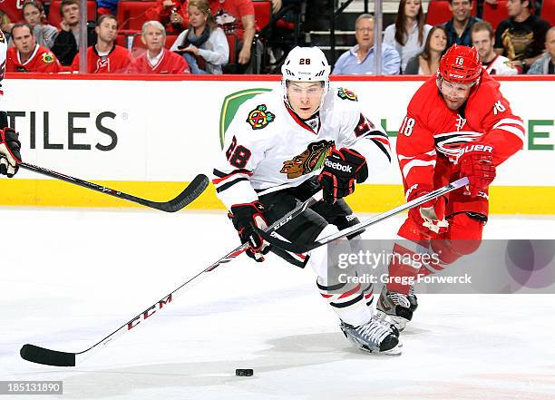 Ben Smith of the Chicago Blackhawks looks to gain control of a loose puck while Radek Devorak of the Carolina Hurricanes defends during their NHL...