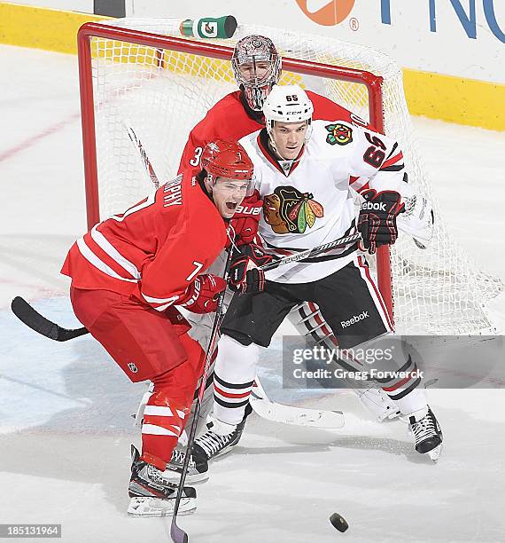 Cam Ward of the Carolina Hurricanes keeps his eye on the puck as teammate Ryan Murphy battles near the crease with Andrew Shaw of the Chicago...