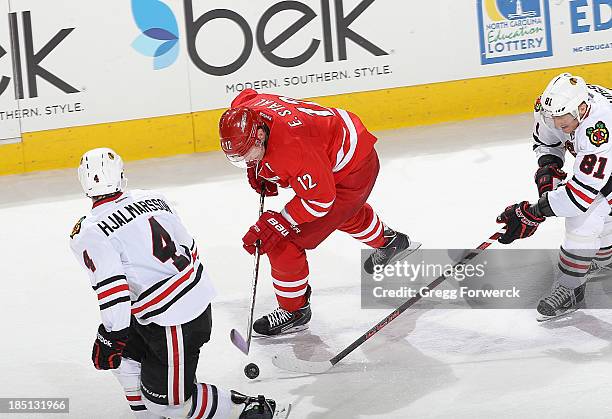 Eric Staal of the Carolina Hurricanes controls the puck past Marian Hossa of the Chicago Blackhawks and teammate Niklas Hjalmarsson during their NHL...