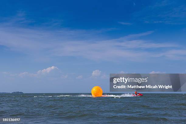 a person plays in a giant ball pulled by waterski - water walking ball stock pictures, royalty-free photos & images