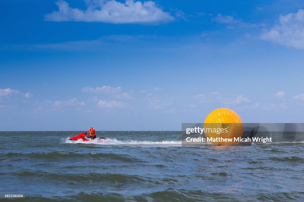 A person plays in a giant ball pulled by waterski