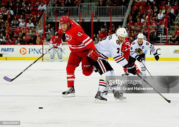 Brent Seabrook of the Chicago Blackhawks and Brett Sutter of the Carolina Hurricanes during play at PNC Arena on October 15, 2013 in Raleigh, North...