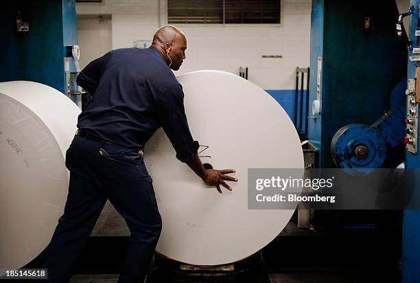 An employee loads a roll of newsprint at the Los Angeles Times Olympic Press facility in Los Angeles, California, U.S, on Wednesday, Oct. 16, 2013....