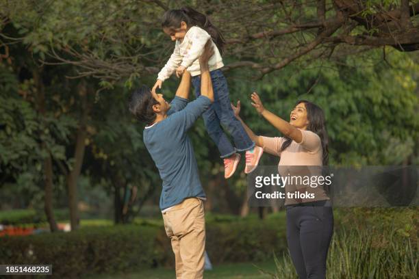 parents lifting daughter in air at garden - india couple lift stock pictures, royalty-free photos & images