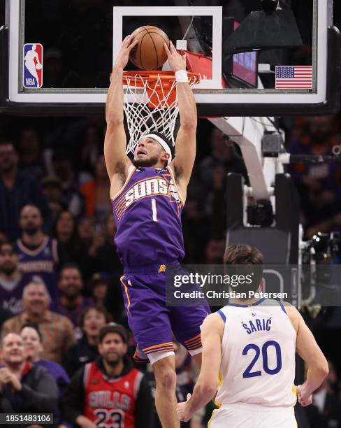 Devin Booker of the Phoenix Suns slam dunks the ball ahead of Dario Saric of the Golden State Warriors during the second half of the NBA game at...