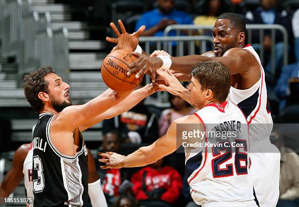 Kyle Korver defends as Elton Brand of the Atlanta Hawks blocks a pass by Marco Belinelli of the San Antonio Spurs at Philips Arena on October 17,...