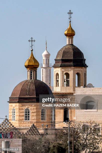 The minaret of a mosque appears behind the domed towers of the Russian Orthodox Church of the Holy Forefathers and Monastery of the Holy Trinity in...