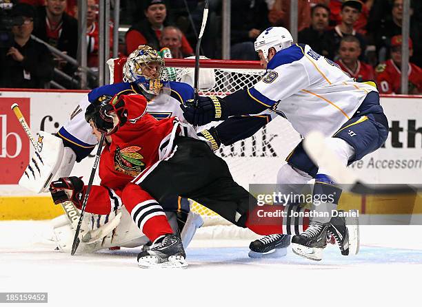 Jay Bouwmeester of the St. Louis Blues shoves Andrew Shaw of the Chicago Blackhawks to the ice in front of Jaroslav Halak at the United Center on...