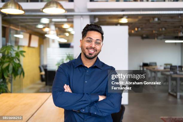 proud young entrepreneur smiling at camera in a coworking - vestimenta casual fotografías e imágenes de stock