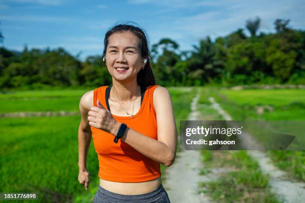 sporty woman jogging in nature field - self-discipline stock pictures, royalty-free photos & images