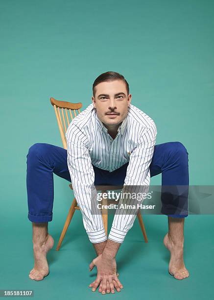 man with arms and legs stretched over a chair - verführung stock-fotos und bilder