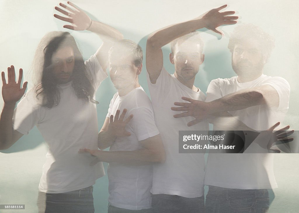 Four men posing behind a silk sheet