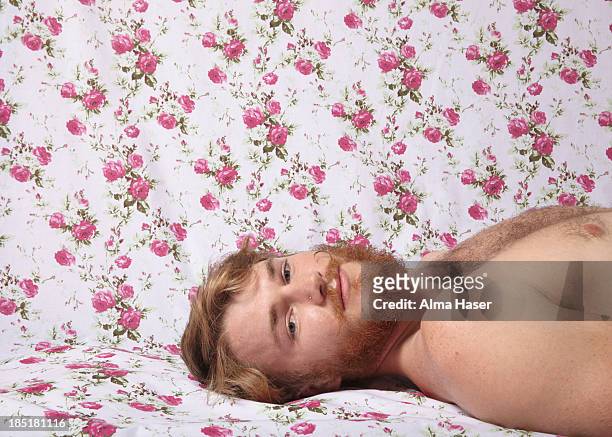 ginger bearded man lying on floral backdrop - hairy men bildbanksfoton och bilder