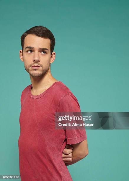 man wearing pink t-shirt with arms behind his back - shy stock pictures, royalty-free photos & images