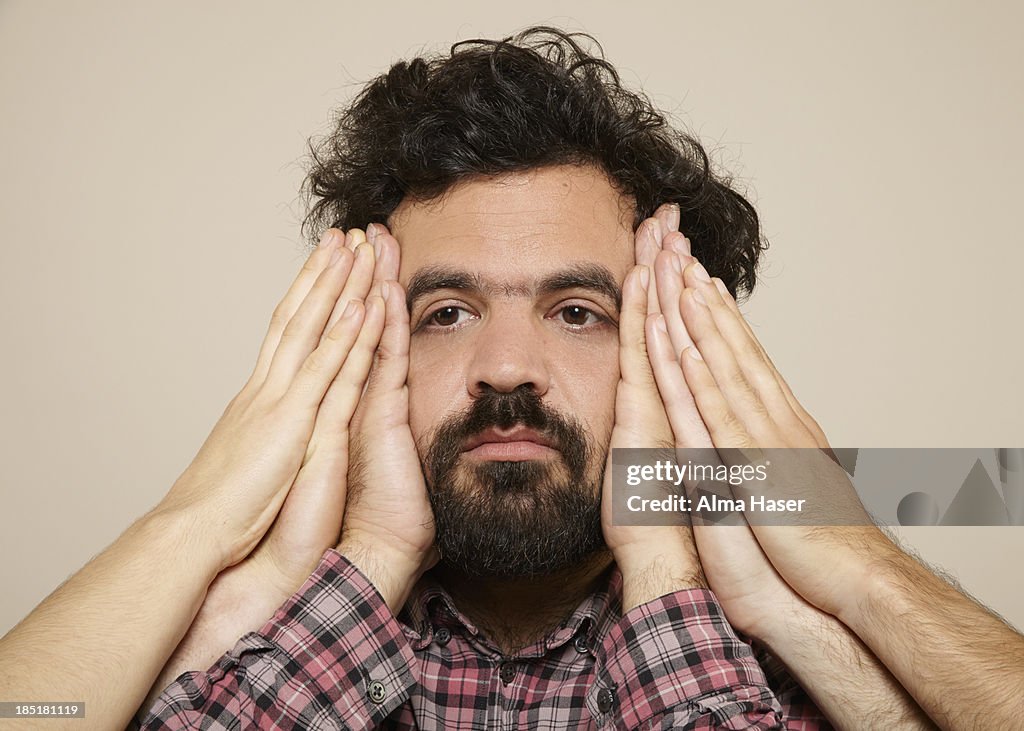 Hairy man with many hands on the sides of his face