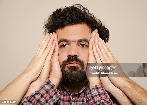 hairy man with many hands on the sides of his face - handen over de oren stockfoto's en -beelden