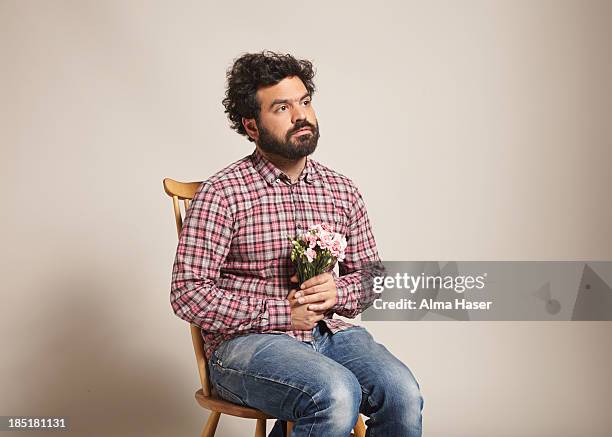 a man sitting with a bunch of pink carnations - dreiviertelansicht stock-fotos und bilder