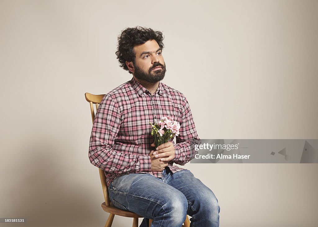 A man sitting with a bunch of pink carnations