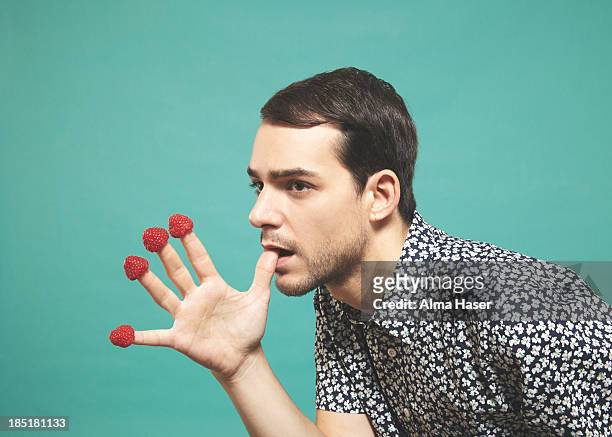 man with raspberries  on finger tips - hand gag foto e immagini stock