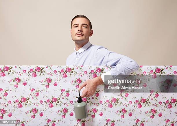 a dapper man spraying flowers on material - 鉛筆ひげ ストックフォトと画像