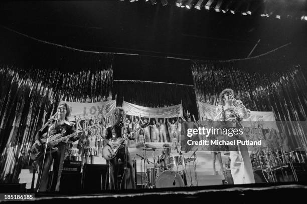 English glam rock singer Gary Glitter performing with the Glitter Band and a large chorus of young women at the Rainbow Theatre, London, November...