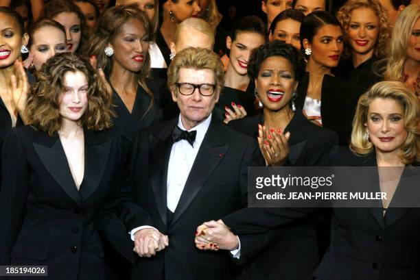 French designer Yves saint-Laurent salutes the crowd with French model Laetitia Casta and French actress Catherine Deneuve at the Centre Georges...