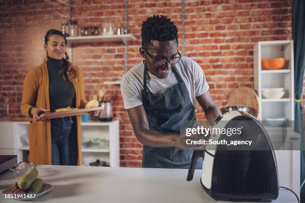 interracial couple cooking together in beautiful kitchen - airfryer stock pictures, royalty-free photos & images