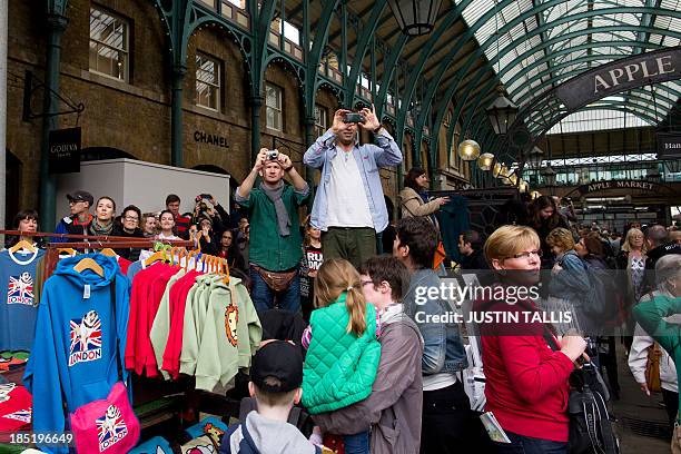 People take photographs as British musician Paul McCartney and his band play an impromptu gig in Covent Garden in London on October 18, 2013. Paul...