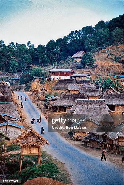 Hmong hilltribe people walk down the road in Ban Songcha, an enchanting village made up of traditional thached huts in the North of Laos. These proud...