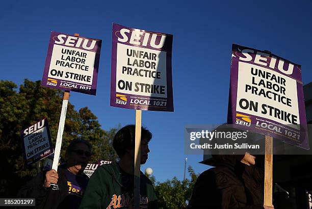 Bay Area Rapid Transit workers carry signs as they picket in front of the Lake Merritt BART station on the first day of the BART strike on October...