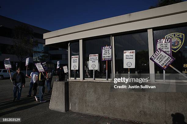 Bay Area Rapid Transit workers carry signs as they picket in front of the Lake Merritt BART station on the first day of the BART strike on October...