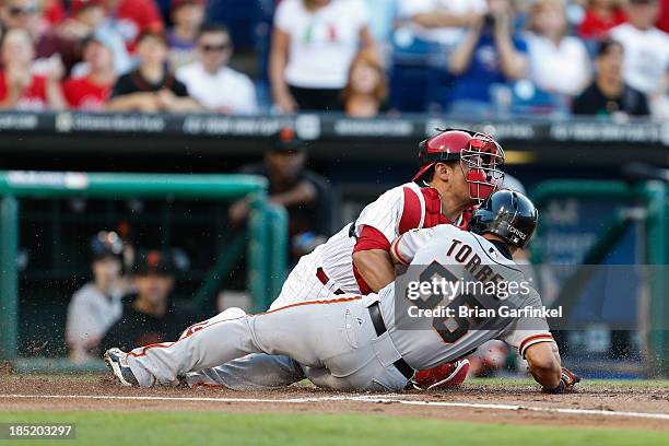 Andres Torres of the San Francisco Giants safely slides into home to score a run past Carlos Ruiz of the Philadelphia Phillies in the first inning of...