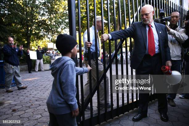 National Zoo Director Dennis Kelly opens the gate to the zoo with the help of an unidentied child on October 18, 2013 in Washington, DC. The...