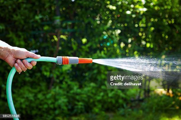 a hand holding a watering hose pipe - hose stockfoto's en -beelden