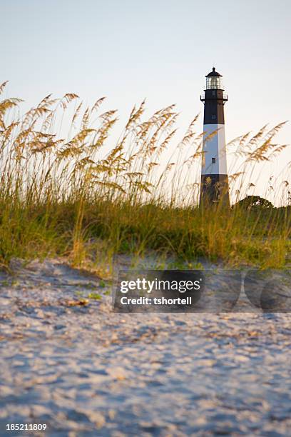 a lighthouse on the beach with sand and grass - savannah stock pictures, royalty-free photos & images