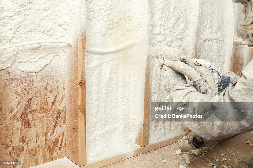 Trabalhador de Construção jogando expansível isolamento de espuma entre travas de parede