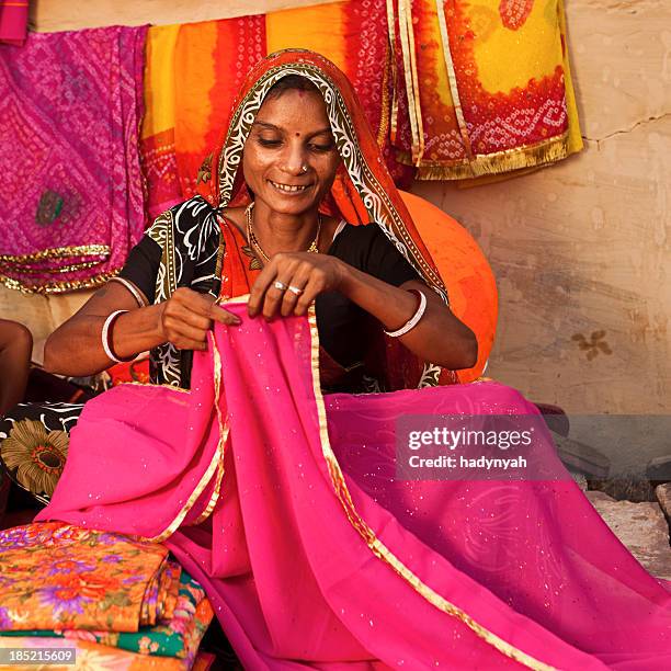 frau farbenfrohe stoffe zu verkaufen - woman in red sari stock-fotos und bilder