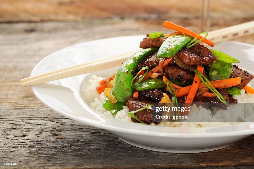 Stir fry meal including beef, peas, carrots, and rice