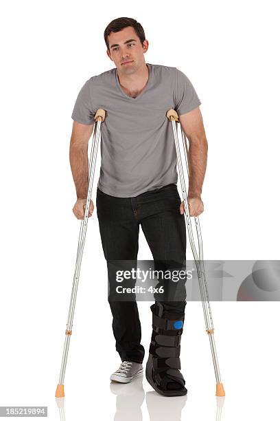 heridas hombre caminando con la ayuda de crutches - crutches fotografías e imágenes de stock