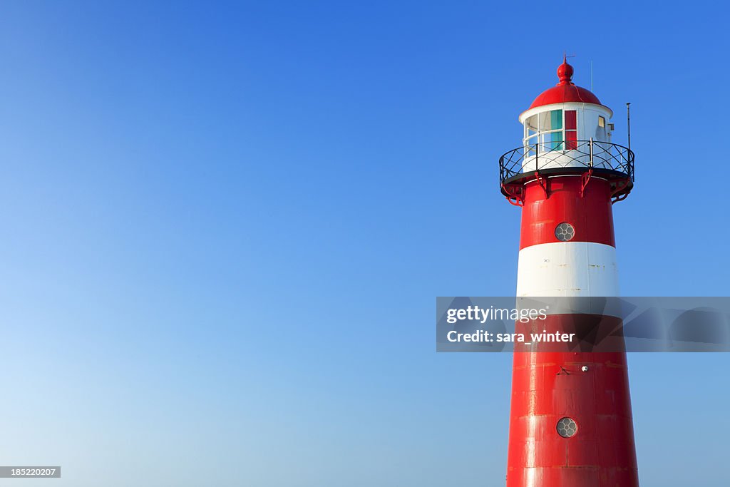 Farol vermelho e branco e um claro céu azul