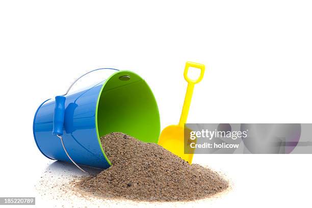 yellow spade, and blue bucket with sand spilling out - bucket and spade stock pictures, royalty-free photos & images