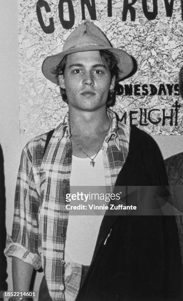 American actor Johnny Depp, wearing a white crew neck t-shirt beneath an open checked shirt and a hat, at The Limelight, a nightclub in New York...