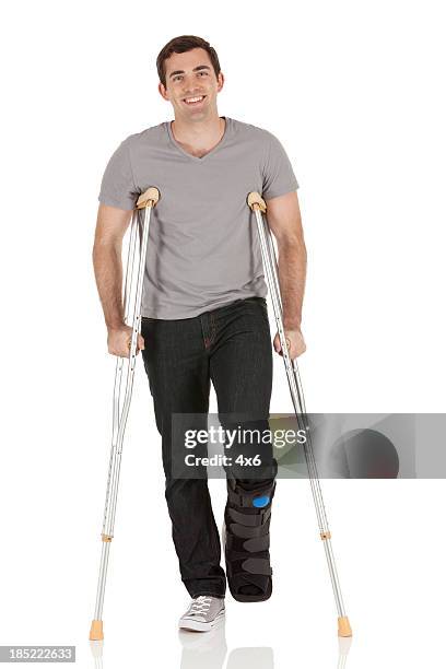 injured man walking with the help of crutches - crutch stock pictures, royalty-free photos & images