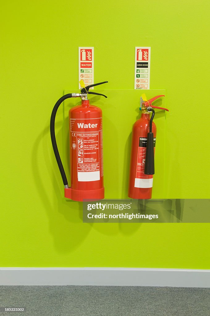 Red fire extinguishers on a green wall