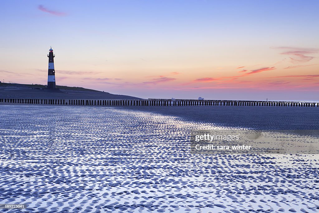 Lighthouse and beach at low tide at dusk, The Netherlands