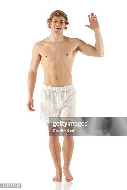 bare chested mann zu fuß und winkt hand - white shorts stock-fotos und bilder