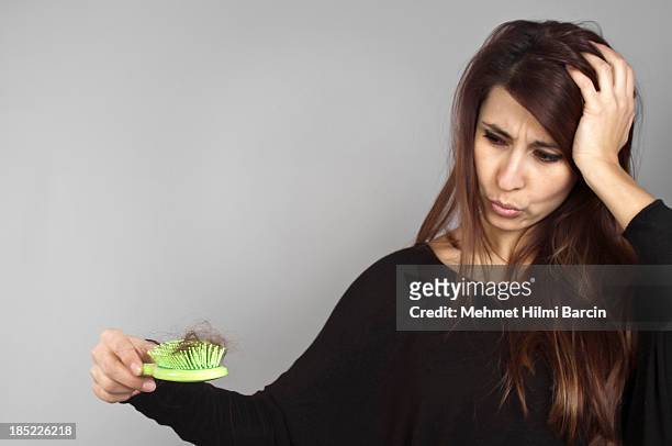 a long hair woman holding a green hairbrush full of hairs - hair loss stock pictures, royalty-free photos & images