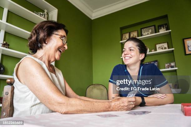 femme âgée jouant aux cartes avec une aide-soignante à domicile - visite à domicile photos et images de collection