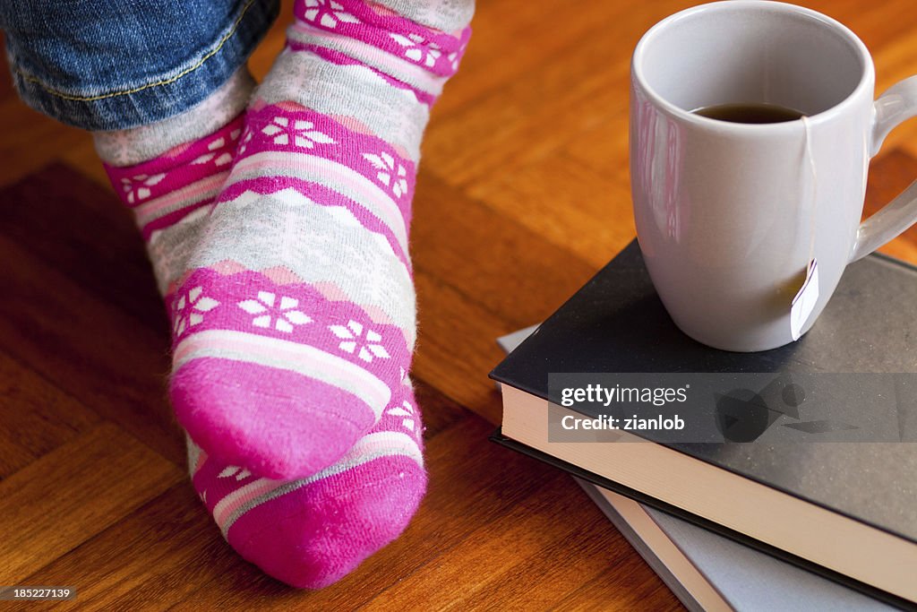 Lustige bunte Socken mit Tasse Tee und Bücher.