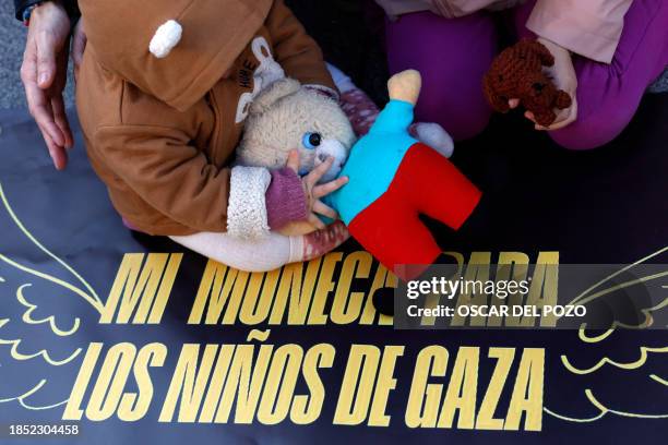 Toddler plays with a soft toy sitting on a banner that reads "My doll for the children from Gaza", as parents and children gather in support of the...